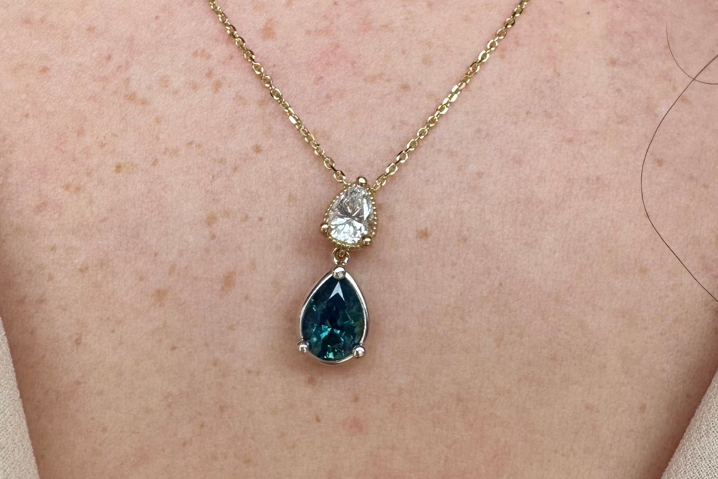 Necklace with a teardrop-shaped gemstone pendant on a person's neck.