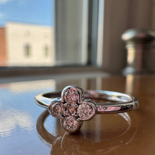 Silver ring with floral design on a reflective surface