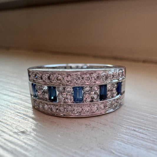 Silver ring with blue gemstones and diamonds on a light wooden surface