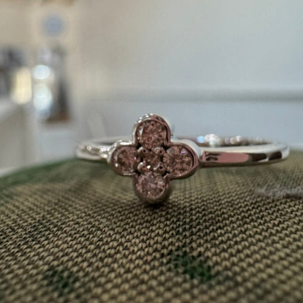 white gold ring with a clover-shaped diamond on a textured surface