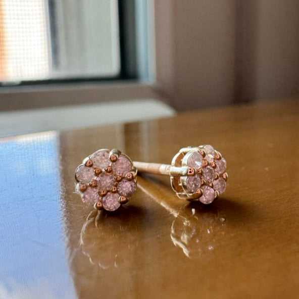 Yellow gold earrings with diamonds on a reflective surface.