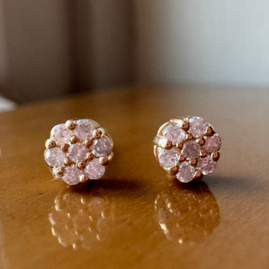 Pair of yellow gold earrings with diamonds on a wooden surface.