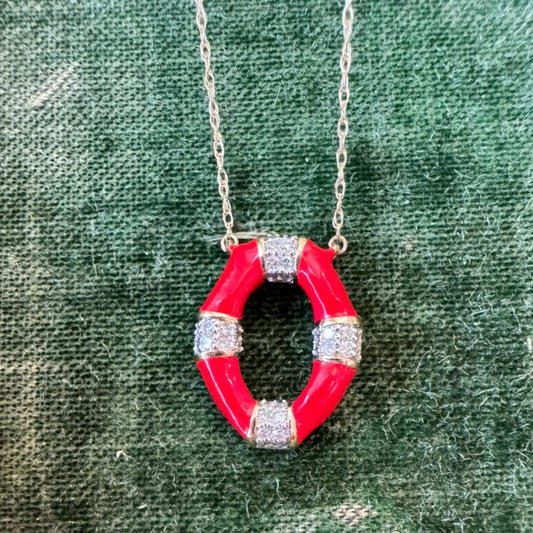 Red enamel pendant with diamonds on a gold chain against a green fabric background