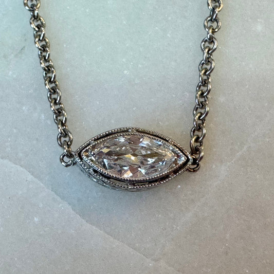 White gold necklace with a marquise-shaped diamond pendant on a marble background