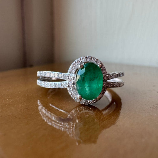 white gold ring with an emerald on a wooden surface