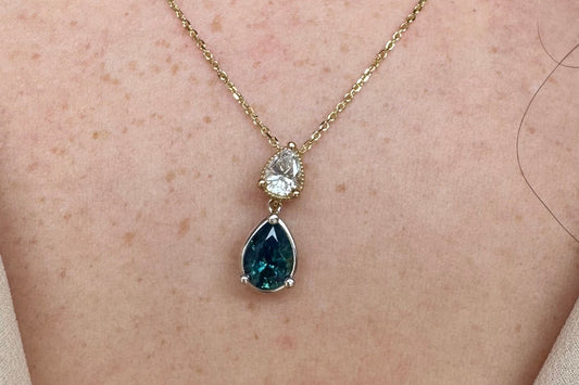 Necklace with a teardrop-shaped gemstone pendant on a person's neck.