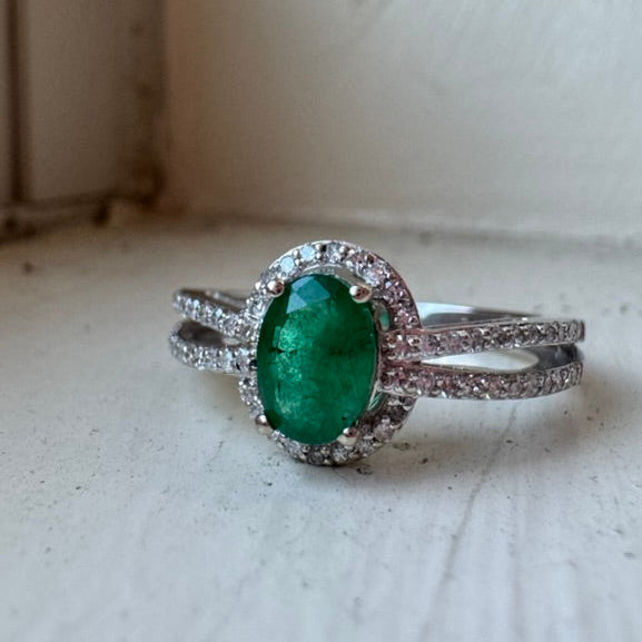 white gold ring with a green gemstone on a light wooden surface