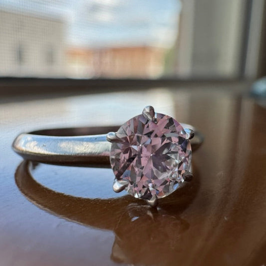 Ring with a diamond gemstone on a reflective surface with a blurred background