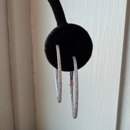 White gold hoop earrings hanging from a black headband against a light wooden background