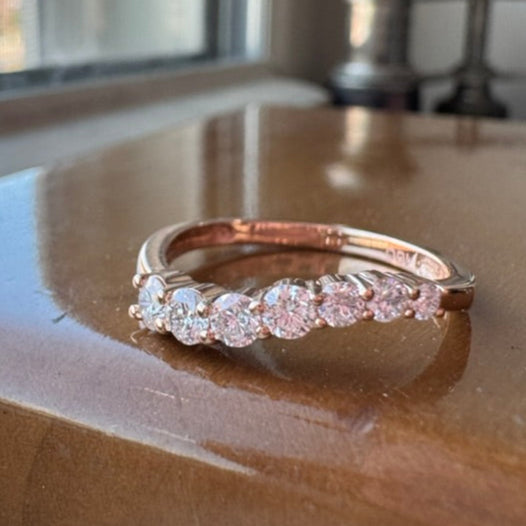 Yellow gold ring with diamonds on a reflective surface near a window