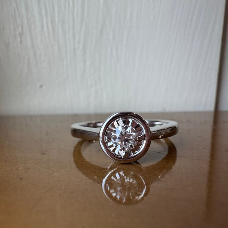 Diamond ring on a reflective surface with a neutral background